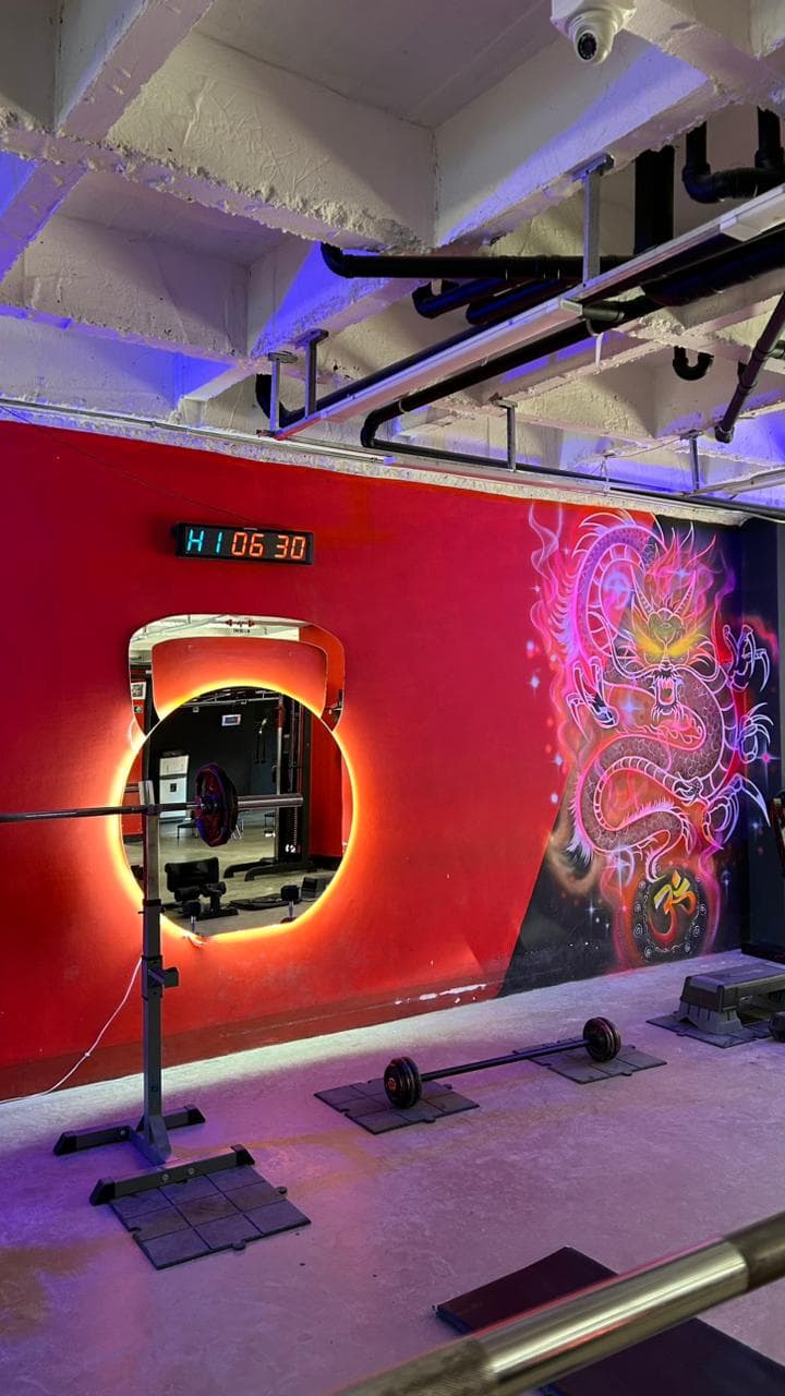 Espejo circular de neón y mural del dragón en Energim